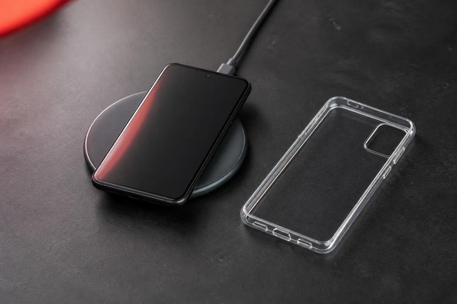 An Android phone on a wireless charging pad beside a clear case